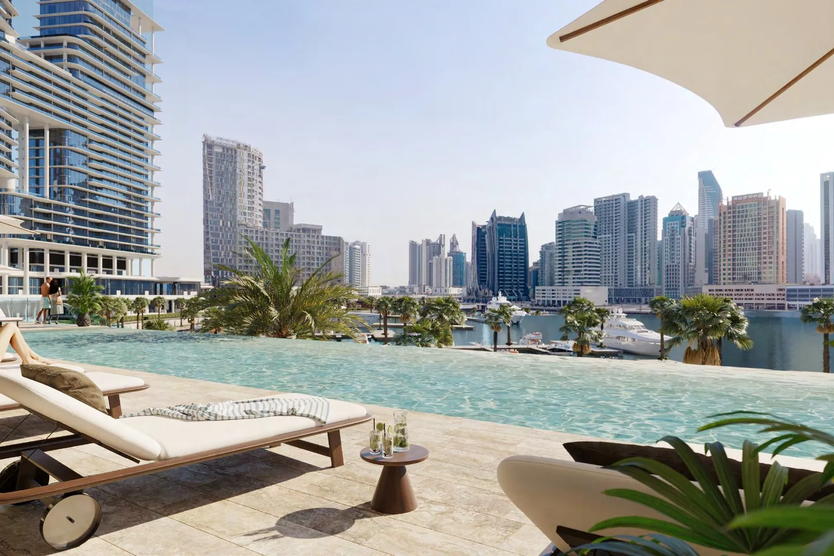 Infinity pool deck with loungers looking over the marina and towers